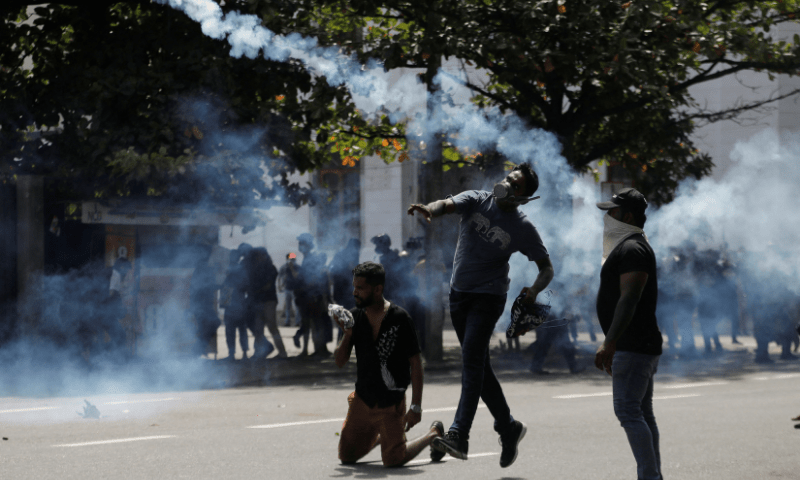 A demonstrator throws back a tear gas grenade towards police members as police use tear gas and water cannons to disperse demonstrators during a protest demanding the resignation of President Gotabaya Rajapaksa, amid the country's economic crisis, near the president's residence in Colombo, Sri Lanka, on Saturday. — Reuters