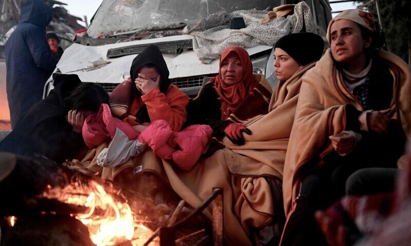 People sit near a bonfire amidst the rubble of collapsed buildings in Kahramanmaras, on February 8, 2023, two days after a 7,8-magnitude earthquake struck southeast Turkey. —AFP