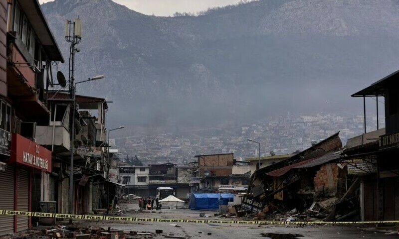 Members of Turkish security stand near a fire as they warm themselves in the streets near the rubble of a collapsed building in the aftermath of a deadly earthquake in Antakya. — Reuters